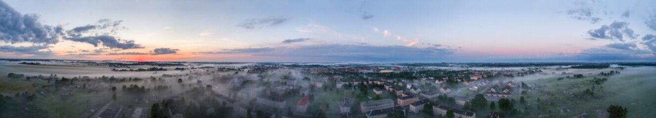 Aerial view of city in fog at amazing sunset. Summer nature landscape. Panorama.