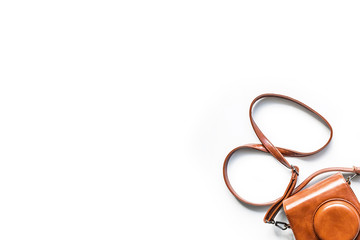 Top view of a small camera in a vintage brown leather case with shoulder strap isolated on a white background