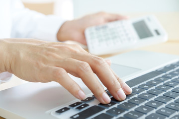 Businessman working at a computer and finds the calculator n the office workplace