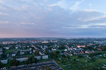 Fototapeta premium Aerial view of city in fog at amazing sunset. Summer nature landscape.