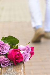 rose bouquet left on a bench men feet leaving on a background
