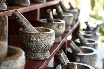 Sets of mortar and pestle in grey and black color granite stone arranging on wooden shelf for sale...