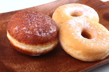 Assorted Homemade Doughnuts with Jelly filled and powdered sugar on wooden salver. Selective focus.