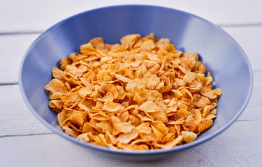 Corn flakes in a plate on a wooden desk.