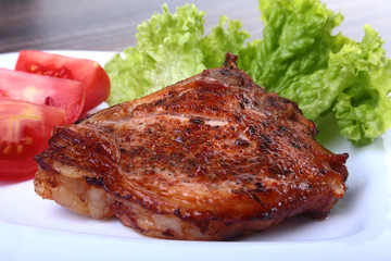 grilled pork chops with tomato, leaves lettuce and ketchup on plate.