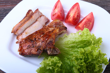grilled pork chops with tomato, leaves lettuce and ketchup on plate.