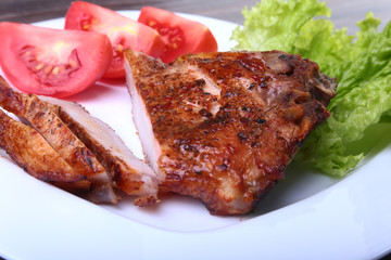grilled pork chops with tomato, leaves lettuce and ketchup on plate.