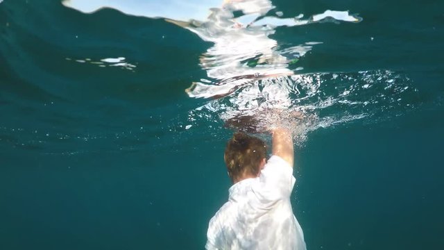 man sinking into the sea, half underwater close up, raw, 4k