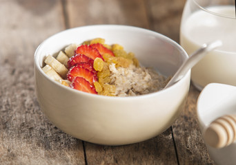 oatmeal porridge with strawberry and banana in wood bowl