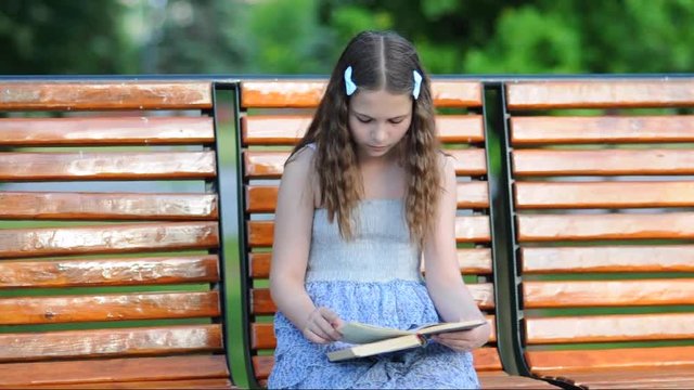 Girl reading a book while sitting on the bench