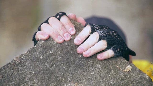 Close up climber hands holding rock. Man alpinist try to pull up on top mountain. caucasian mountaineer wearing yellow shirt, cap, gloves.