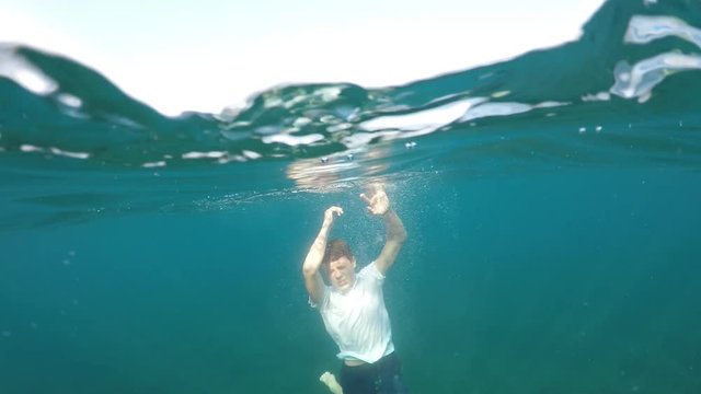 man sinking into the sea, half underwater close up, raw, 4k
