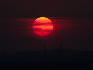 beautiful sunset with wind turbines on the hill in summer, silhouettes