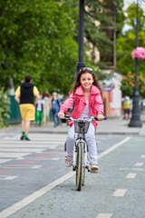 Fototapeta premium Cute kid in safety helmet biking outdoors. Little girl on a red bicycle Healthy preschool children summer activity.