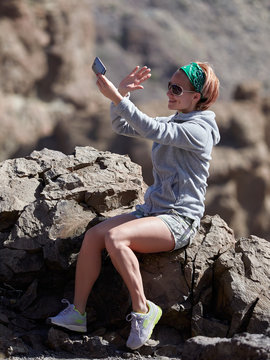 Young female traveler taking selfie on the beautiful rocky background in Teide Natural Park , Tenerife