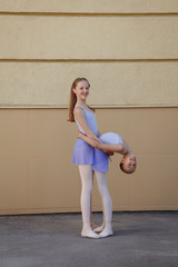 Ballet dancers dancing on street. Young ballerinas on yellow background full length