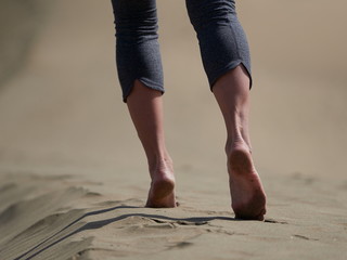 bare feet of young woman jogging/walking on the beach at sunrise