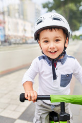 Fototapeta na wymiar Little boy kid in helmet ride a bike in city park. Cheerful child outdoor.