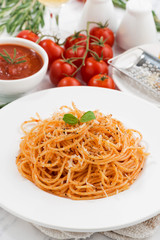 pasta with tomato sauce on a plate and ingredients, vertical