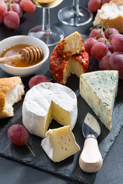 molded cheeses, wine and grapes on a blackboard, vertical