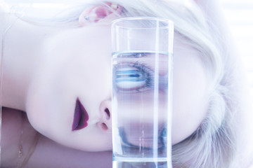 girl looks at camera through glass with water toned image