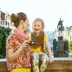 Naklejka premium mother and daughter in Prague viewing photos on camera