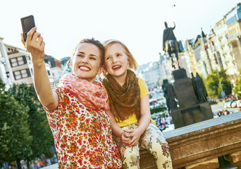 mother and daughter with digital camera taking selfie in Prague