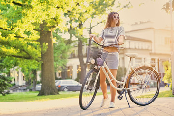 Obraz premium A woman with city bicycle in a summer outdoor park.