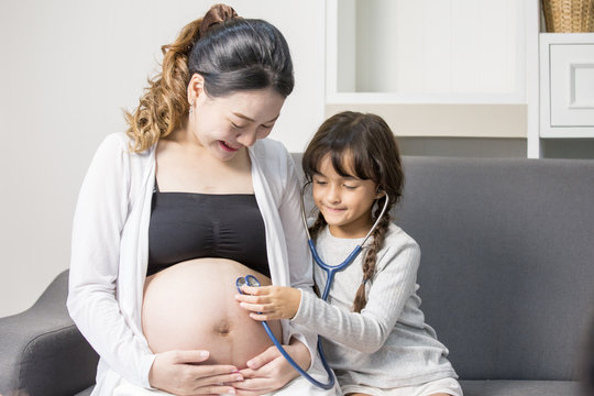 Little cute girl using stethoscope check stomach her mother