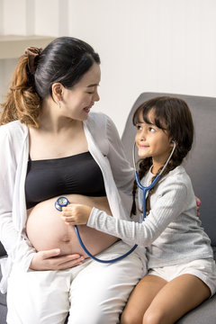 Little cute girl using stethoscope check stomach her mother