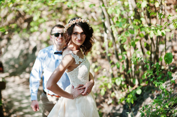 Fantastically-looking couple strolling in the forest on their wedding day.