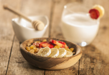 oatmeal porridge with strawberry and banana in wood bowl