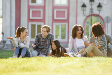 Smiling young students sitting studying outdoors