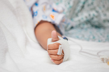 Child's patient hand with saline intravenous (iv) drip in the hospital