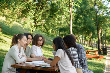 Students sitting and studying outdoors while talking.