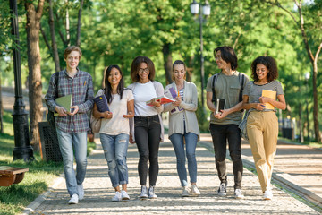 Group of happy young students walking outdoors