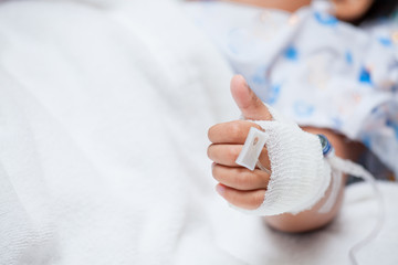 Child's patient hand with saline intravenous (iv) drip in the hospital