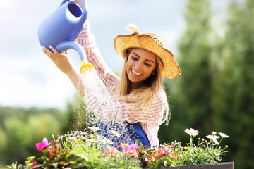 Woman watering plants outside in summer