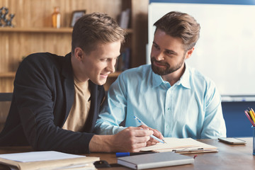 Cheery youthful guys filling job application in office