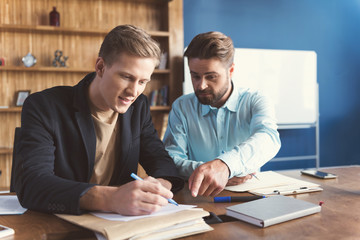 Jolly and concentrated two males doing employment test in office