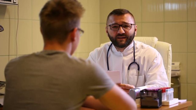 Doctor talking with patient in the office and smiling to the camera
