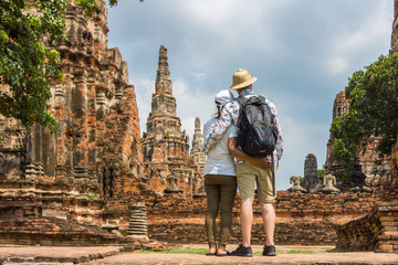 Romantic couple, European and Asian, embracing each other at old temple ruins. Foreign tourists go sightseeing in Ayutthaya Historical Park, Thailand, Southeast Asia. - obrazy, fototapety, plakaty