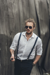 Obraz premium Stylish young man smoking cigarette and holding lighter while walking with hand in pocket