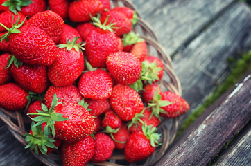 Strawberry in wicker plate on wooden background