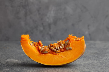 Halloween pumpkin slice with seeds on gray textured stone background