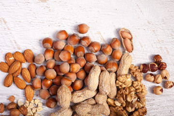 Mix of variety of nuts on white wooden background. Healthy raw snaks