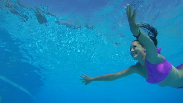 Young beautiful woman swims under water in the pool
