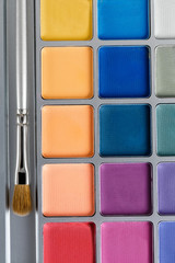 professional cosmetics. Palette of multicolored eye shadow and makeup brush, top view