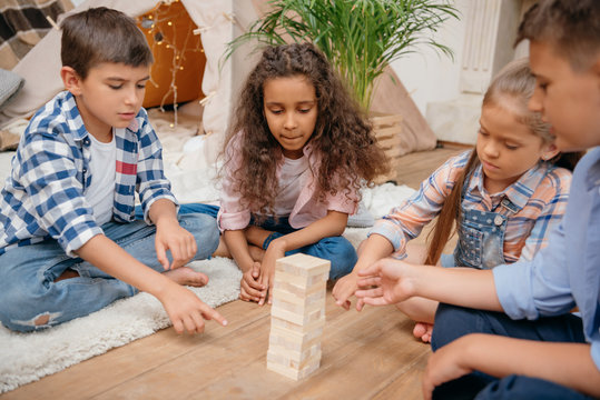 multicultural group of children playing blocks wood game together at home