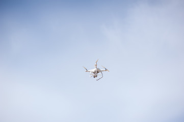 Quadcopter or drone holds video using a digital camera on the blue sky background